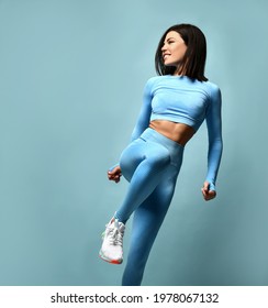 Slender beautiful female athlete with a perfect body in sportswear on a blue background. Sexy woman in blue sportswear looks towards the free space for text. Concept of comfortable clothes for fitness