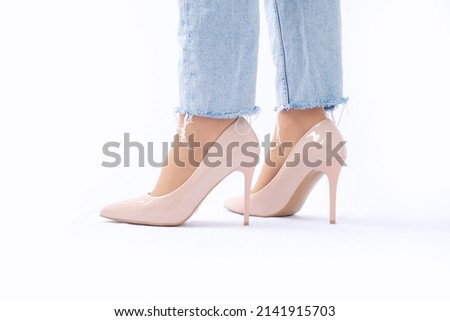 Slender female legs in patent leather shoes with high heels. Light blue ripped jeans. Fashion and Style. Side view