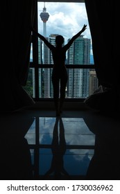 A slender girl is looking at the city through a large window. High floor. Kuala Lumpur / Malaysia - 04.17.2020 - Shutterstock ID 1730036962