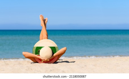 A slender girl on the beach in a straw hat in the colors of the flag of Bulgaria. The concept of a perfect vacation in a resort in the Bulgaria. Focus on the hat.
