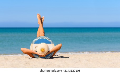 A slender girl on the beach in a straw hat in the colors of the Argentina flag. The concept of a perfect vacation in a resort in the Argentina. Focus on the hat.