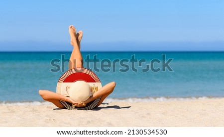 A slender girl on the beach in a straw hat in the colors of the Egypt flag. The concept of a perfect vacation in a resort in the Egypt. Focus on the hat.