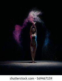 Slender girl posing in color powder cloud