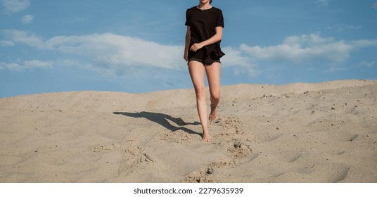 A slender girl in short shorts and a black T-shirt walks through the desert. Creative image for your design or illustrations. - Shutterstock ID 2279635939