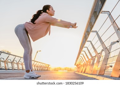 Slender girl in sporty outfit is training on the bridge early in the morning - Shutterstock ID 1830256109