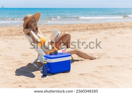  a slender girl in a swimsuit sits on a sun lounger sunbathes and reads a book on the beach