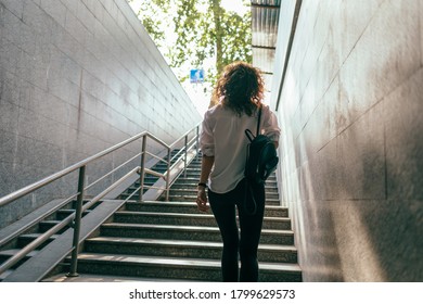 Slender girl in a white shirt with a handbag climbs the stairs from the underpass - Shutterstock ID 1799629573