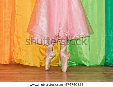 Slender legs of a ballerina clad in Pointe shoes, standing on toes closeup