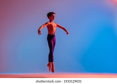 Slender Teen Ballet Boy Jumps Barefoot Under Colored Light.