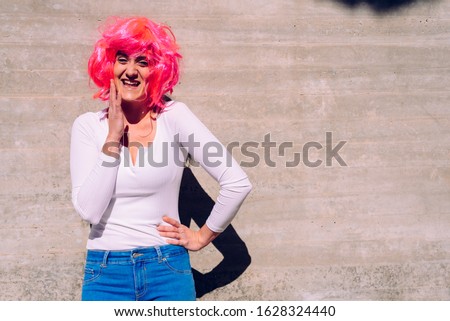 Slender and ugly woman with colorful wig posing ridiculously.