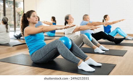 Slender young woman practicing pilates with ball in exercise room during pilates classes. Persons doing pilates in fitness hall - Powered by Shutterstock