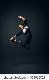 Slender young woman in sportswear jumping for joy. Studio shot over black background.   - Shutterstock ID 335910029