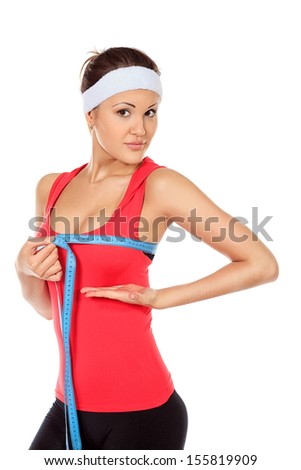 Slender young woman in sportswear measuring her breast. Isolated over white.