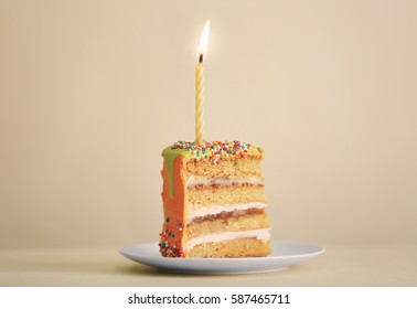 Slice of birthday cake with candle on color background