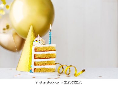 Slice Of Birthday Cake With Single Blue Birthday Candle And Gold Birthday Balloons