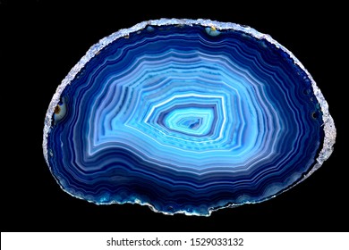 Slice of blue agate stone specimen, with rings of different blue shades, against a black limbo background