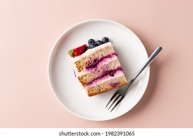 Slice Of Blueberry Cake Decorated With Fresh Berries On White Plate. Delicious Layered Cake. Pink Background. Top View