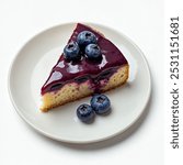 Slice of blueberry cake, with a glossy glaze, placed on a simple white plate with some berries on the top, top view isolated on white background