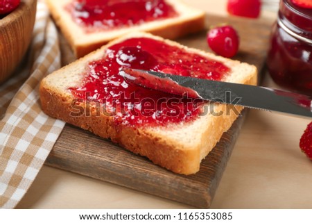 Slice of bread with delicious strawberry jam on board, closeup