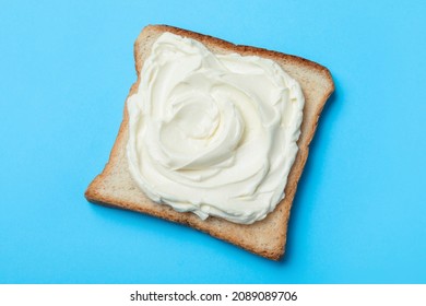 Slice Of Bread With Tasty Cream Cheese On Light Blue Background, Top View