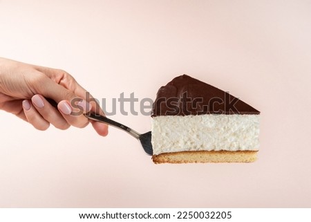 Slice of cake in hand. Hand  female holding slice of cake. isolated background. Side view. Sweet birds milk cake