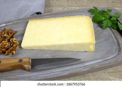 Slice Of Cantal Cheese On A Cutting Board