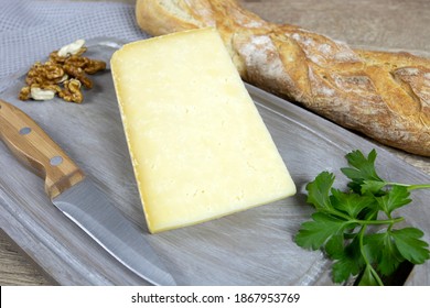 Slice Of Cantal Cheese On A Cutting Board