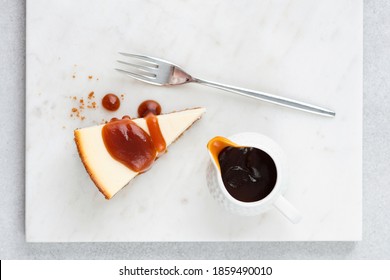 Slice Of Cheesecake With Salted Caramel Sauce On Marble Board, Top View