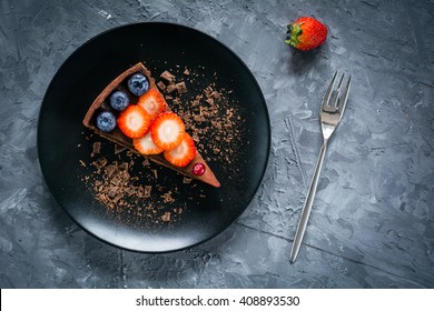Slice of chocolate mousse tart decorated with fresh berries on black plate. Table top view food - Powered by Shutterstock