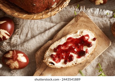 A slice of Czech sweet Easter cake called mazanec with butter and cranberry jam on a wooden cutting board