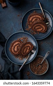 Slice Of Delicious Chocolate Roll Cake With Chocolate Cream, Dark Blue Background. Top View