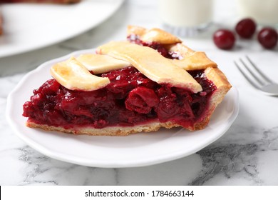 Slice of delicious fresh cherry pie on white marble table, closeup