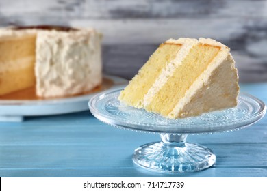 Slice of delicious vanilla cake on blue wooden table