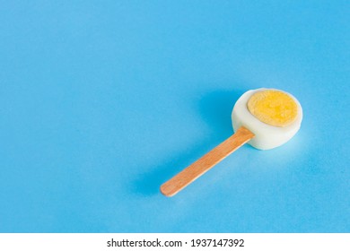 A Slice Of Easter Egg On A Stick Like Ice Cream On A Blue Background. Minimal Creative Concept Of Easter Or Food.