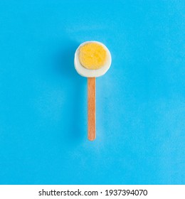 A Slice Of Easter Egg On A Stick Like Ice Cream On A Blue Background. Minimal Creative Concept Of Easter Or Food. Flat Lay