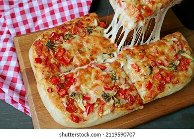 Slice of Fresh Baked Pizza Alla Pala with Mouthwatering Stretching Cheese Being Taken from Breadboard
