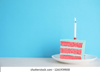 Slice of fresh delicious birthday cake with candle on table against color background. Space for text