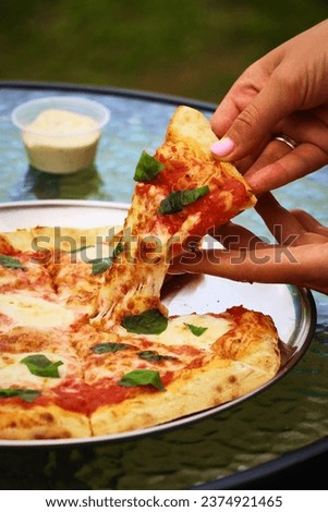 A slice of fresh, hot, homemade, deliciouse italian pizza with bacon, onion, mushrooms and ham in woman's hands. Vertical closeup view from side