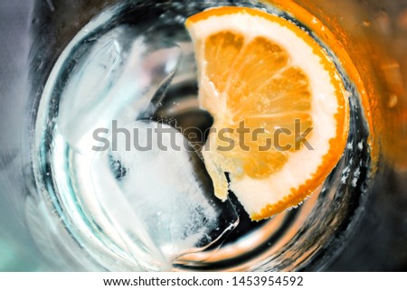 Slice of fresh orange with ice cubes in a glass, flat lay perspective, cool and refreshing summer beverage