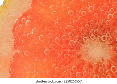 Slice of grapefruit in sparkling water. Grapefruit slice covered by bubbles in carbonated water. Grapefruit slice in water with bubbles. Macro shot of red grapefruit in bubble water. Tropical fruit. - Powered by Shutterstock