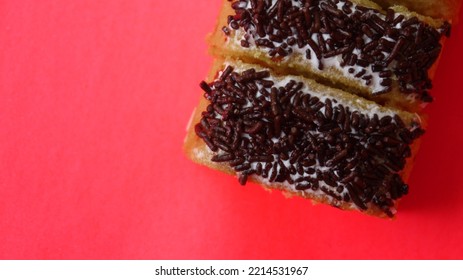 Slice Of Handmade Sponge Cake With Chocolate Sprinkles On A Red Background