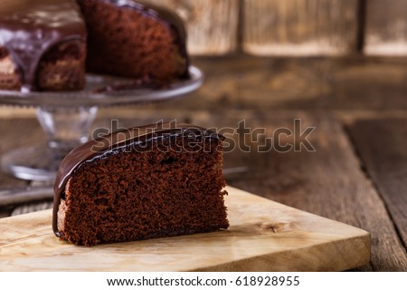 Slice of homemade chocolate cake on wooden cutting board, rustic style
