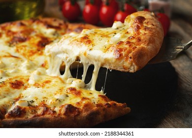 A slice of hot Italian pizza with stretching cheese. Pizza four cheeses with basil on a wooden background. - Powered by Shutterstock