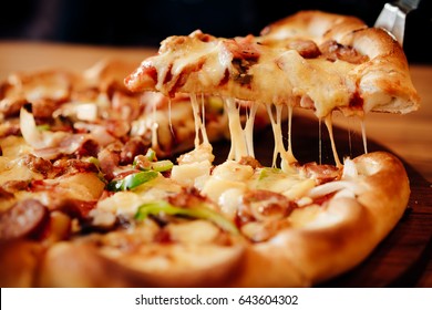 Slice of hot pizza large cheese lunch or dinner crust seafood meat topping sauce. with bell pepper vegetables delicious tasty fast food italian traditional on wooden board table classic in side view .