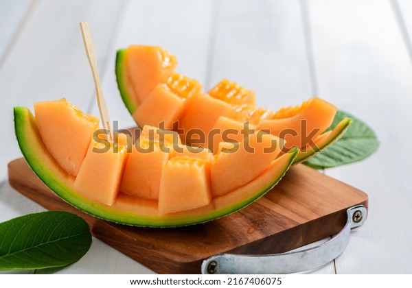 slice of japanese melons,\
orange melon or cantaloupe melon on white wood background, summer\
fruits