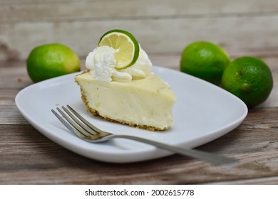 Slice Of Key Lime Pie On Plate With Limes