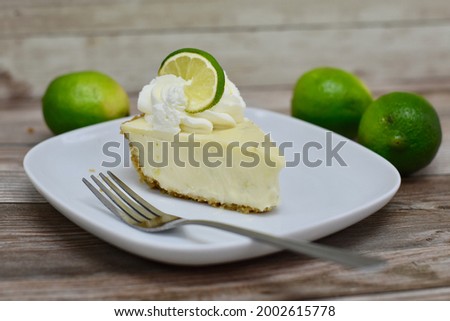 Slice of key lime pie on plate with limes