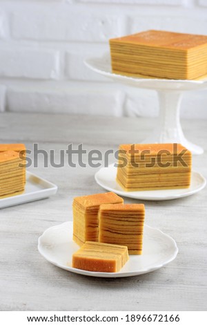Slice Lapis Legit on Plate and Whole Cake Full Square Plain Indonesian Layer Cake or Lapis Legit on Cake Stand, White Concept for Homemade Bakery Stock photo © 