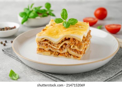 Slice of Lasagna bolognese with meat sauce and bechamel with melted cheese on top and fresh basil. Italian cusine. Copy space