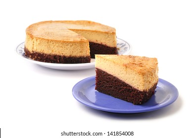 Slice Of Layered Chocolate Mexican Flan On Plate Next To Whole Pie On White Background